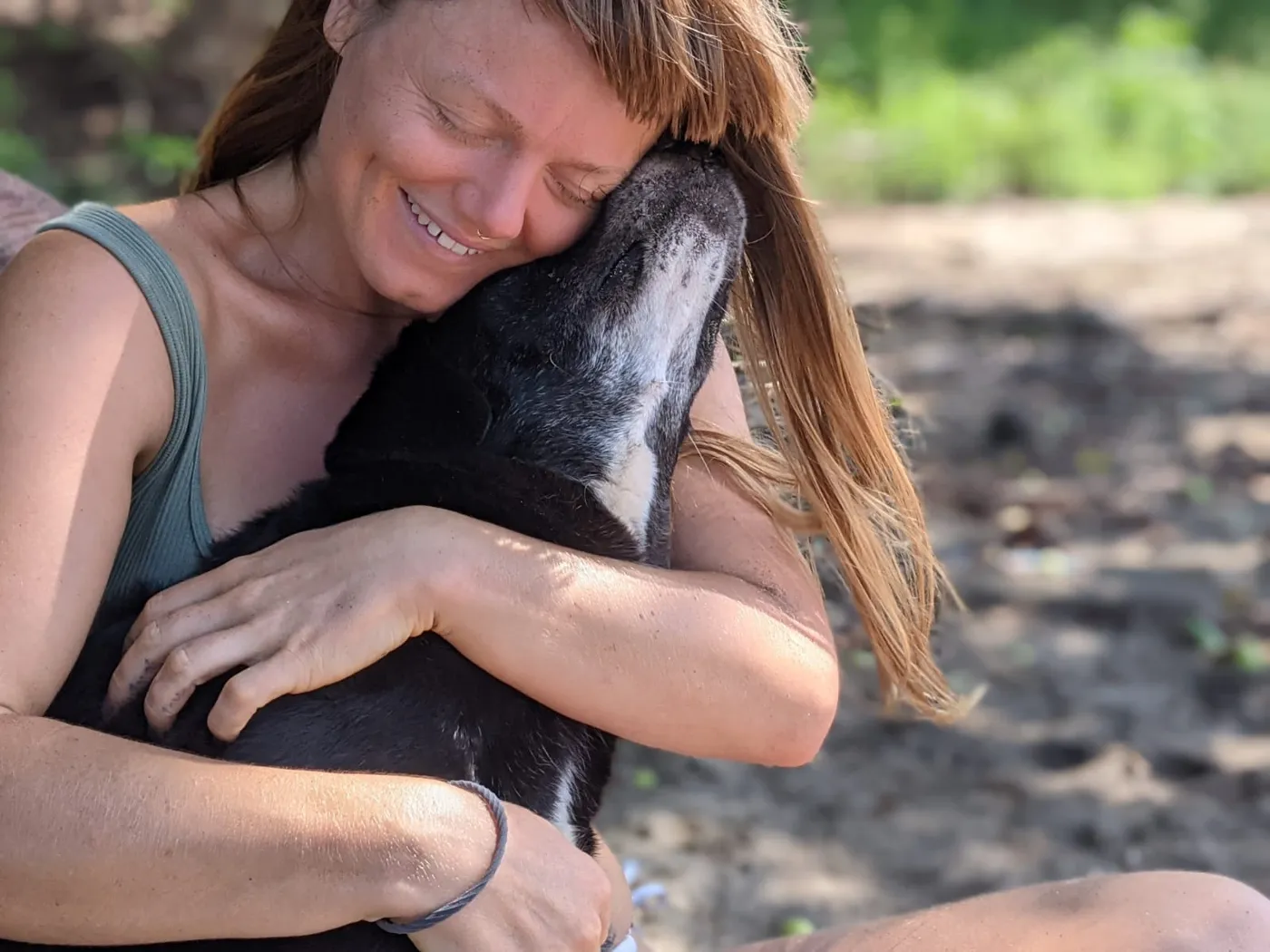 Cassandra hugging a dog, eyes closed and smiling